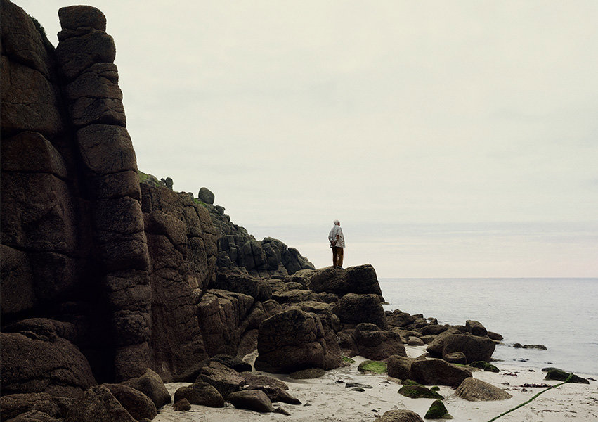 John Le Carré on a rocky beach looking out to the sea