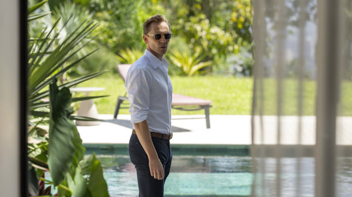 Man in white shirt and sunglasses standing in front of swimming pool
